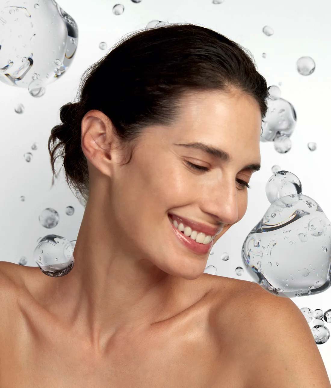 Woman with radiant skin surrounded by hyaluronic acid gel droplets representing Profhilo bioremodeling and deep hydration