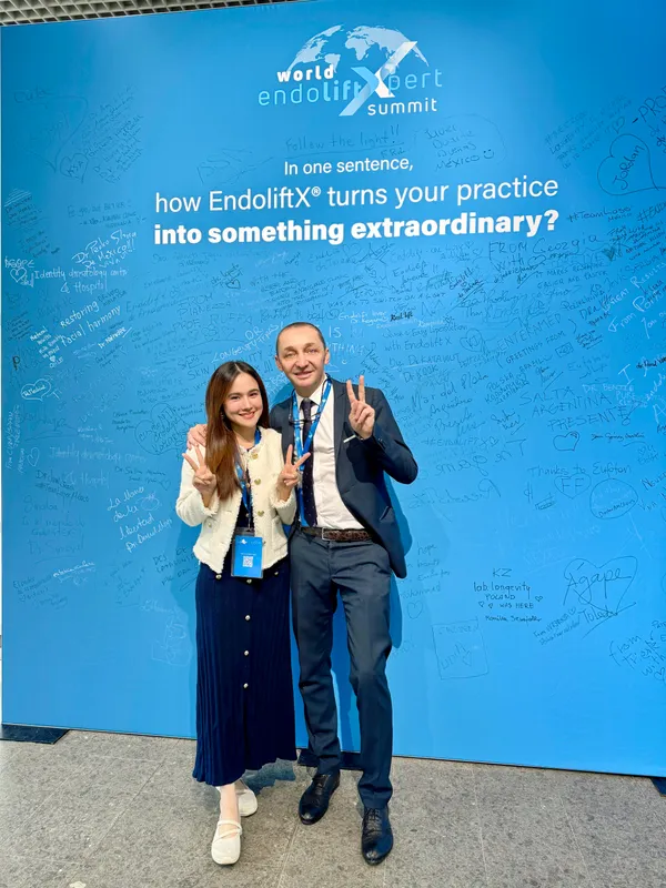Dr. Pang posing with an EndoliftX expert in front of the World EndoliftXpert Summit signature wall